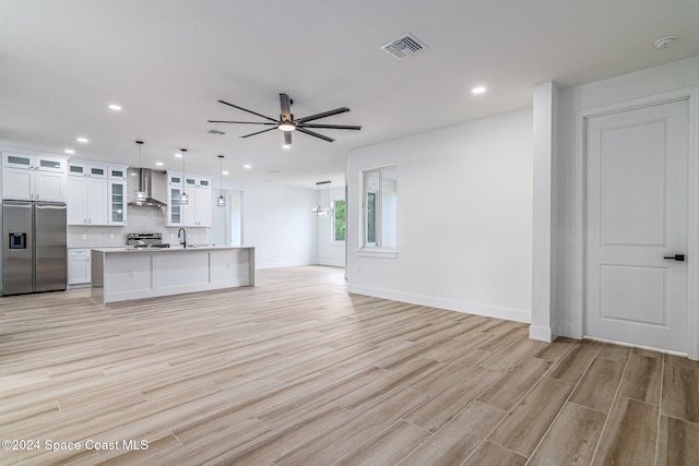 kitchen featuring white cabinets, decorative light fixtures, light hardwood / wood-style floors, and appliances with stainless steel finishes