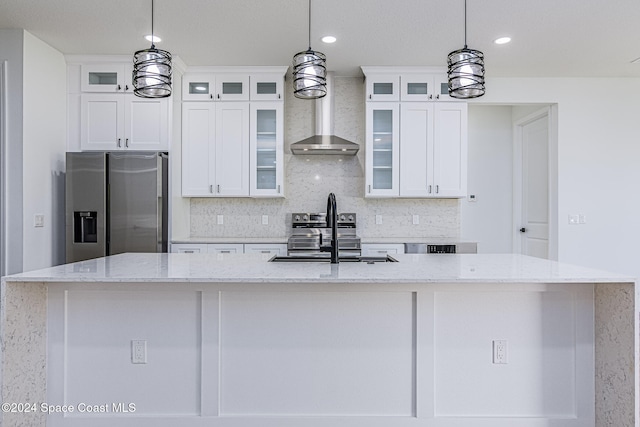 kitchen with light stone countertops, an island with sink, stainless steel appliances, and decorative light fixtures