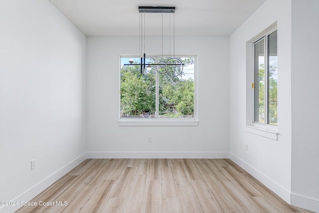 unfurnished dining area featuring light hardwood / wood-style flooring and a notable chandelier