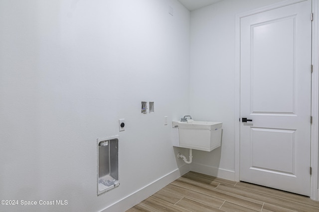 laundry room featuring electric dryer hookup, light wood-type flooring, sink, and hookup for a washing machine