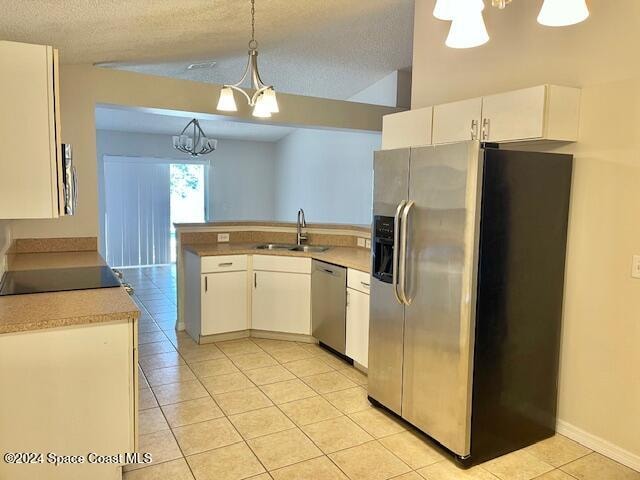 kitchen featuring white cabinets, sink, stainless steel appliances, and hanging light fixtures