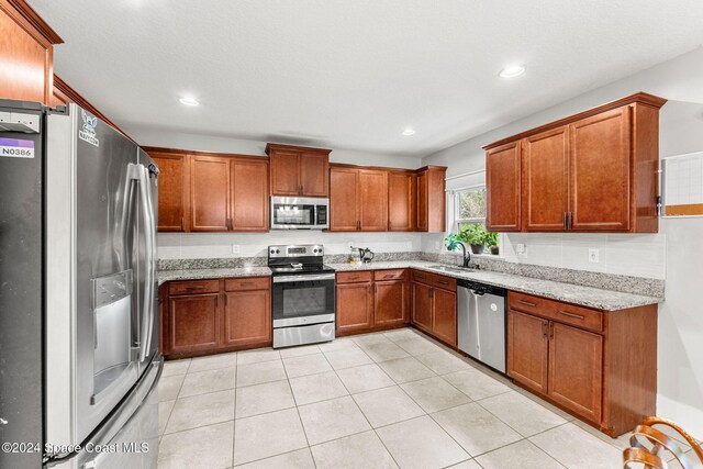 kitchen with light stone counters, sink, light tile patterned floors, and appliances with stainless steel finishes