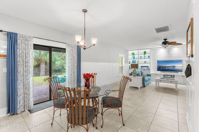 tiled dining area with a textured ceiling and ceiling fan with notable chandelier