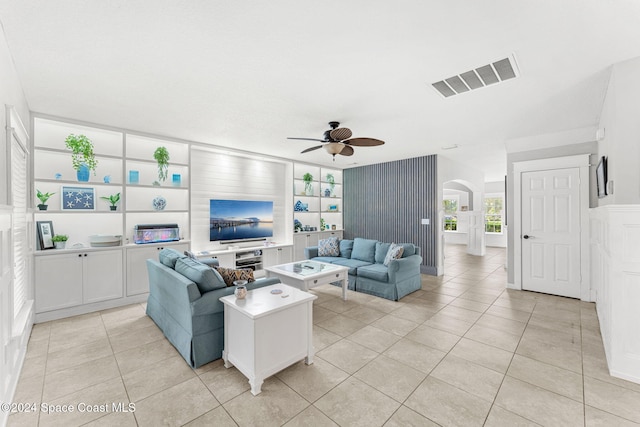 tiled living room with built in features and ceiling fan