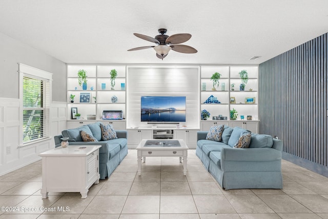 living room featuring built in shelves, light tile patterned floors, and a textured ceiling