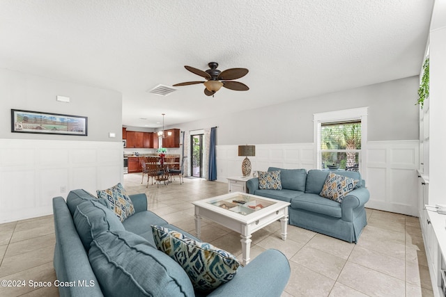 living room featuring ceiling fan, light tile patterned flooring, and a textured ceiling