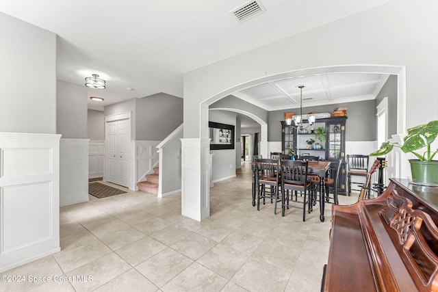 tiled dining space featuring crown molding and a notable chandelier