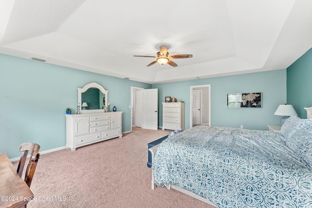 bedroom featuring ceiling fan, a raised ceiling, and light carpet