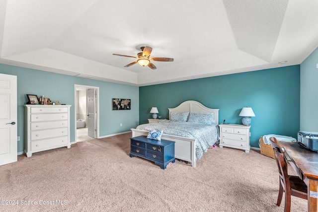 carpeted bedroom with a textured ceiling, ceiling fan, a raised ceiling, and ensuite bathroom