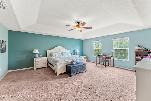 bedroom featuring ceiling fan, light carpet, and a tray ceiling