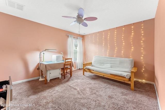 living area featuring carpet, ceiling fan, and a textured ceiling