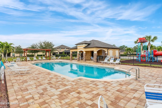 view of pool featuring a playground and a patio area