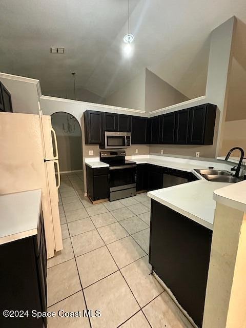 kitchen with sink, stainless steel appliances, kitchen peninsula, lofted ceiling, and light tile patterned floors