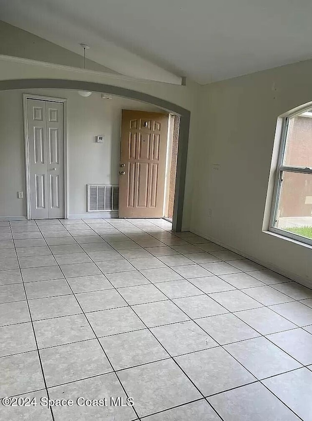 empty room with vaulted ceiling and light tile patterned flooring