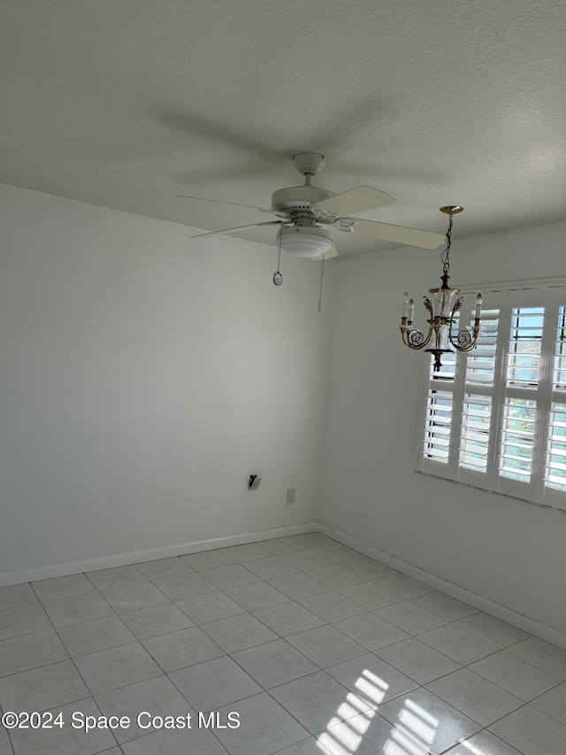 spare room with light tile patterned floors, ceiling fan with notable chandelier, and a textured ceiling