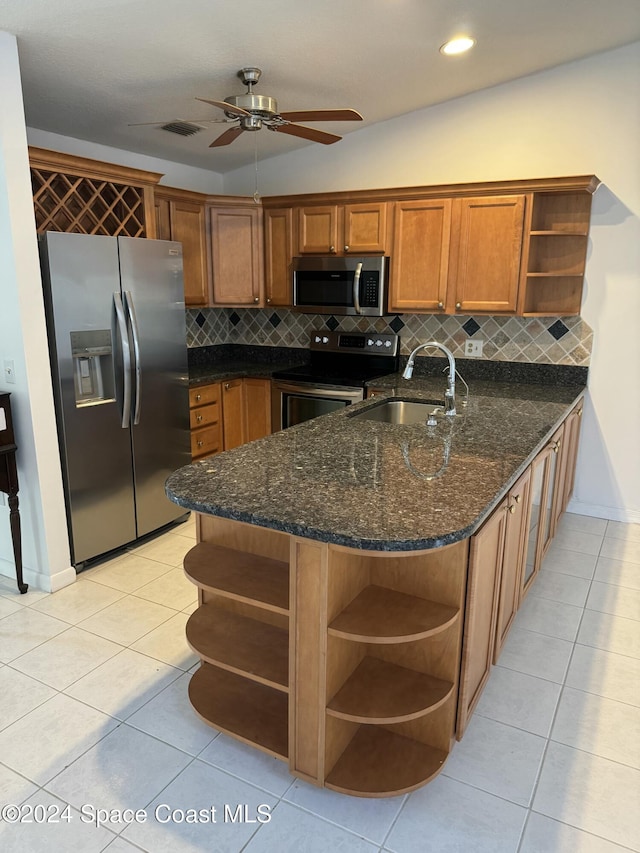 kitchen featuring kitchen peninsula, backsplash, stainless steel appliances, sink, and dark stone countertops