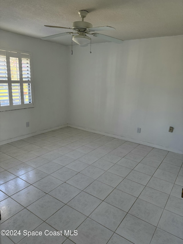 tiled empty room featuring ceiling fan and a textured ceiling