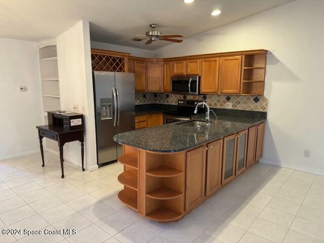 kitchen with kitchen peninsula, ceiling fan, dark stone counters, and appliances with stainless steel finishes