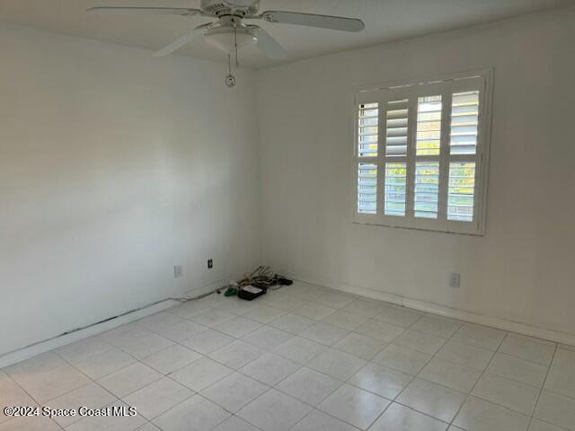 tiled empty room featuring ceiling fan