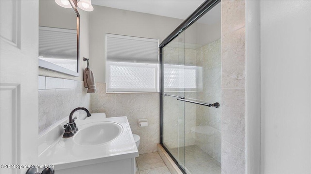 bathroom with vanity, toilet, a shower with door, and tile walls