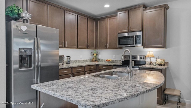 kitchen featuring dark brown cabinetry, light stone countertops, and appliances with stainless steel finishes