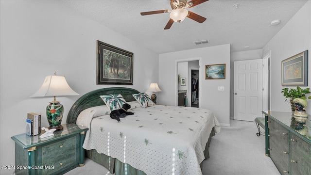 bedroom featuring a textured ceiling, light colored carpet, and ceiling fan