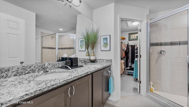 bathroom featuring tile patterned flooring, vanity, an enclosed shower, and a textured ceiling