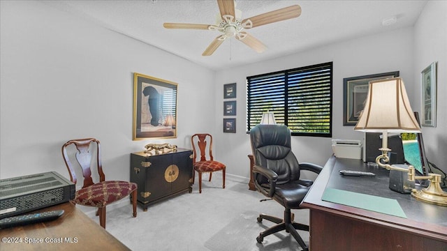 home office featuring light carpet, ceiling fan, and a textured ceiling