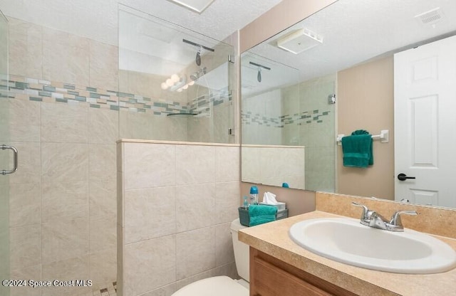 bathroom featuring a shower with door, vanity, a textured ceiling, and toilet