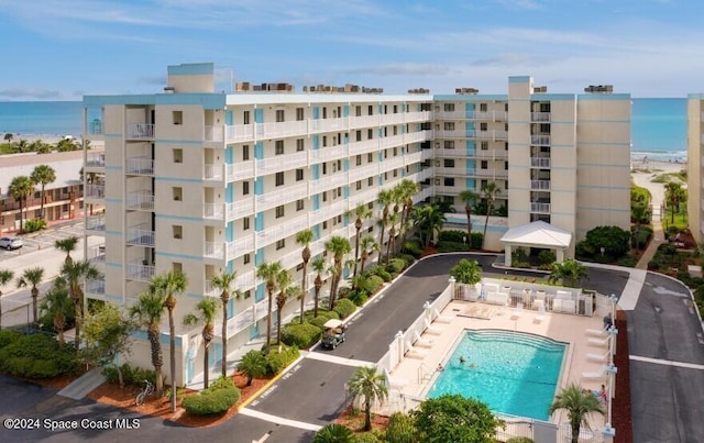 view of building exterior with a community pool and a water view