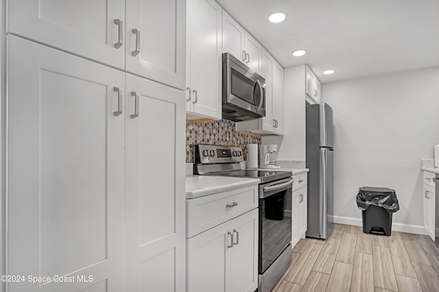 kitchen with white cabinets, light hardwood / wood-style floors, backsplash, and appliances with stainless steel finishes