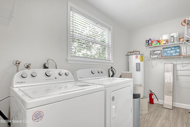 laundry area featuring washing machine and clothes dryer, electric water heater, and light hardwood / wood-style flooring