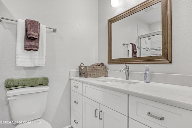 bathroom with a shower with door, vanity, and toilet