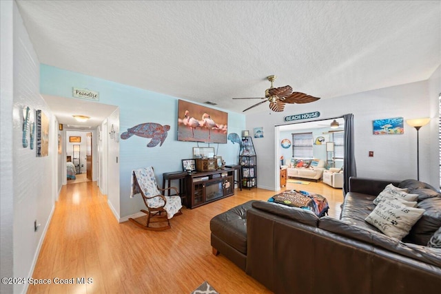 living room with hardwood / wood-style flooring, ceiling fan, and a textured ceiling