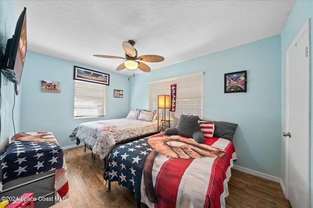 bedroom with ceiling fan, dark wood-type flooring, and a textured ceiling