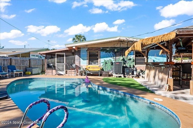 view of pool with a sunroom and an outdoor bar