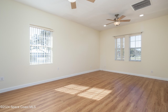 empty room with ceiling fan, light wood-type flooring, and a wealth of natural light