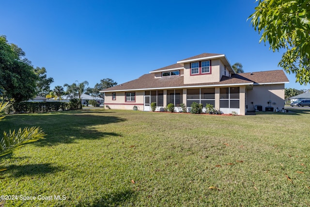 back of house featuring a lawn and a sunroom