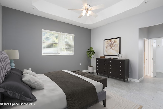 bedroom featuring ceiling fan and a raised ceiling