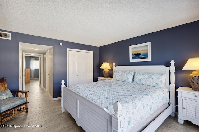 bedroom with a textured ceiling, light hardwood / wood-style floors, and a closet