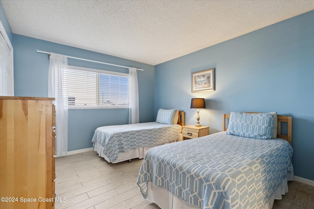 bedroom featuring a textured ceiling and light hardwood / wood-style flooring