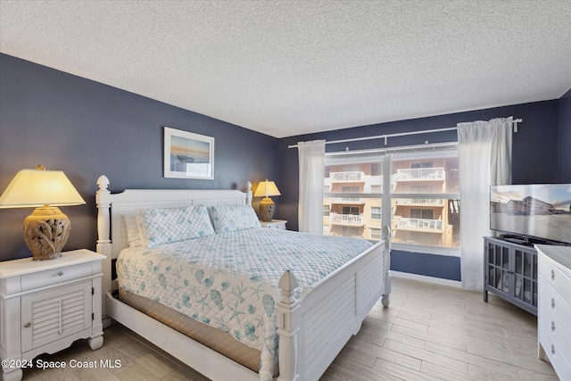 bedroom with a textured ceiling and light hardwood / wood-style floors