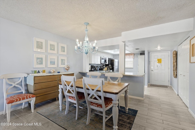 dining space featuring light hardwood / wood-style floors, a textured ceiling, and a notable chandelier