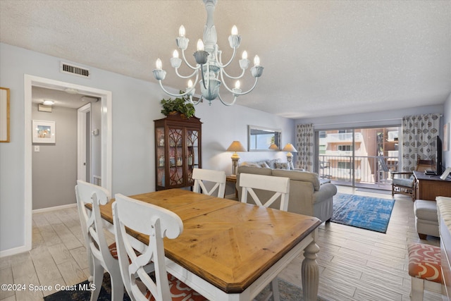 dining area with a textured ceiling, light hardwood / wood-style floors, and an inviting chandelier