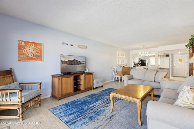 living room featuring an inviting chandelier, a textured ceiling, and light hardwood / wood-style flooring