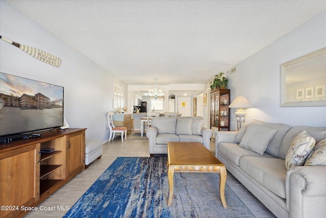 living room featuring a notable chandelier, a textured ceiling, and light hardwood / wood-style flooring