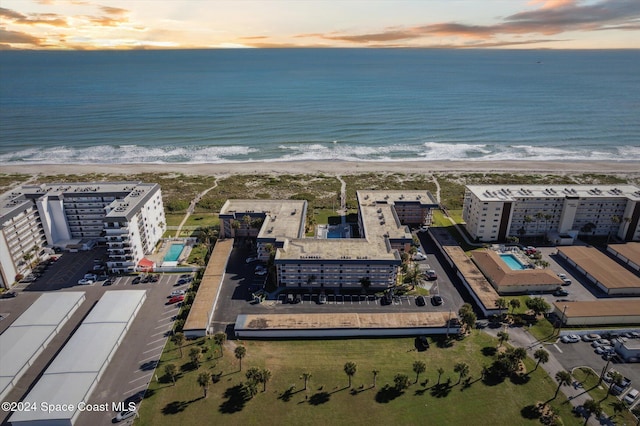 aerial view at dusk with a beach view and a water view