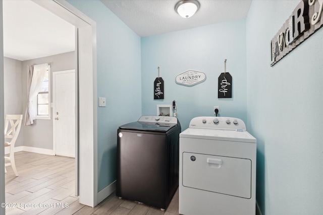 laundry area featuring washer and dryer, a textured ceiling, and light wood-type flooring