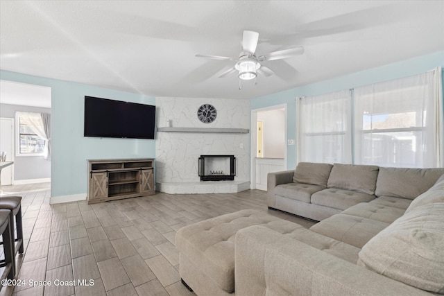 living room featuring ceiling fan, light wood-type flooring, and a fireplace