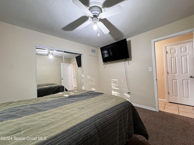 bedroom with ceiling fan, a closet, light carpet, and a textured ceiling